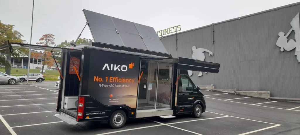 Otwarta boczna ekspozycja AIKO Van z przeszklonym wejściem i panelami fotowoltaicznymi nad pojazdem